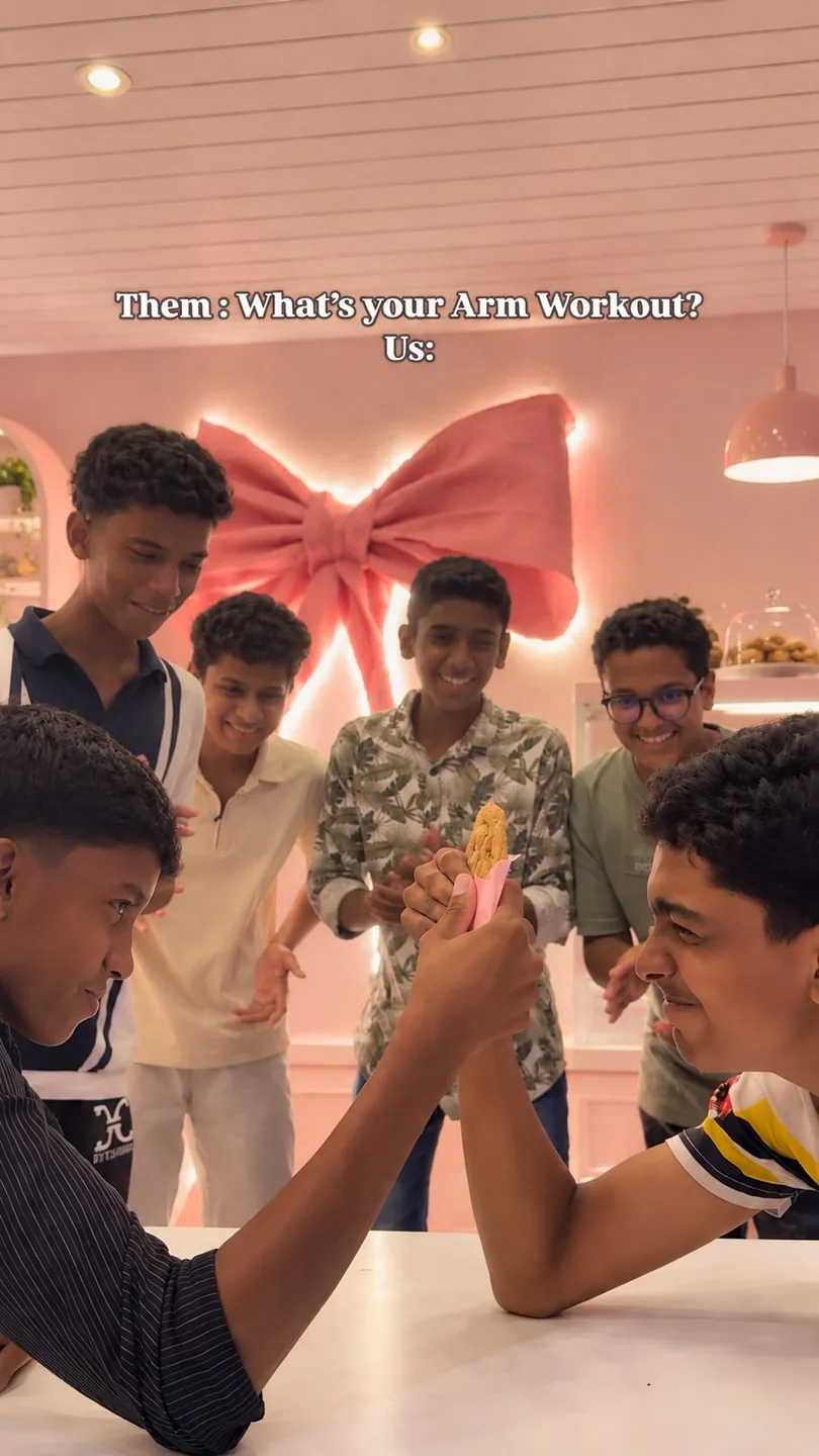 Friends arm wrestling on a café table under the big pink bow