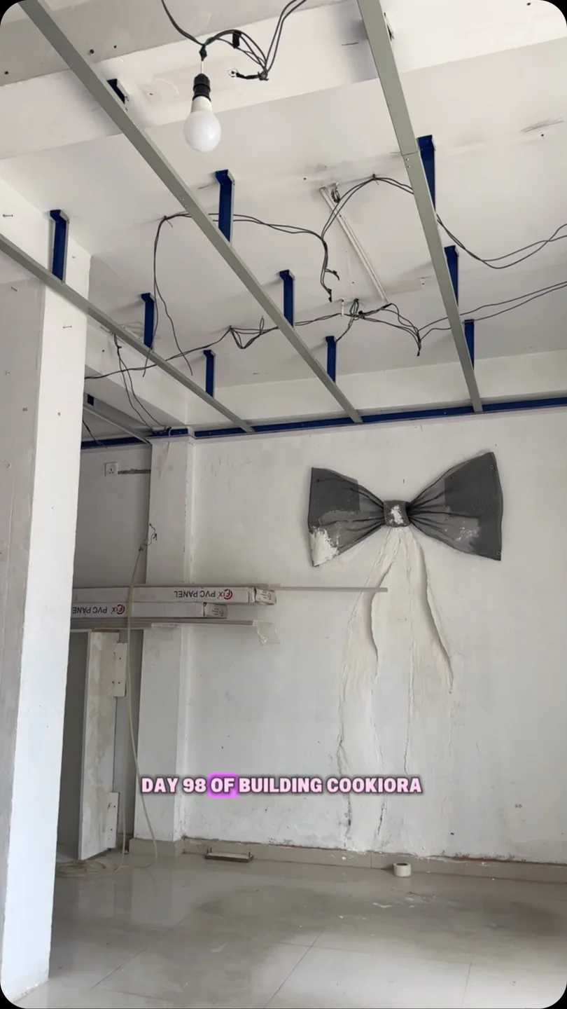 The bare shell of the café on day 98 of building Cookiora: a bare ceiling frame, loose wires and a grey bow sculpted onto the wall